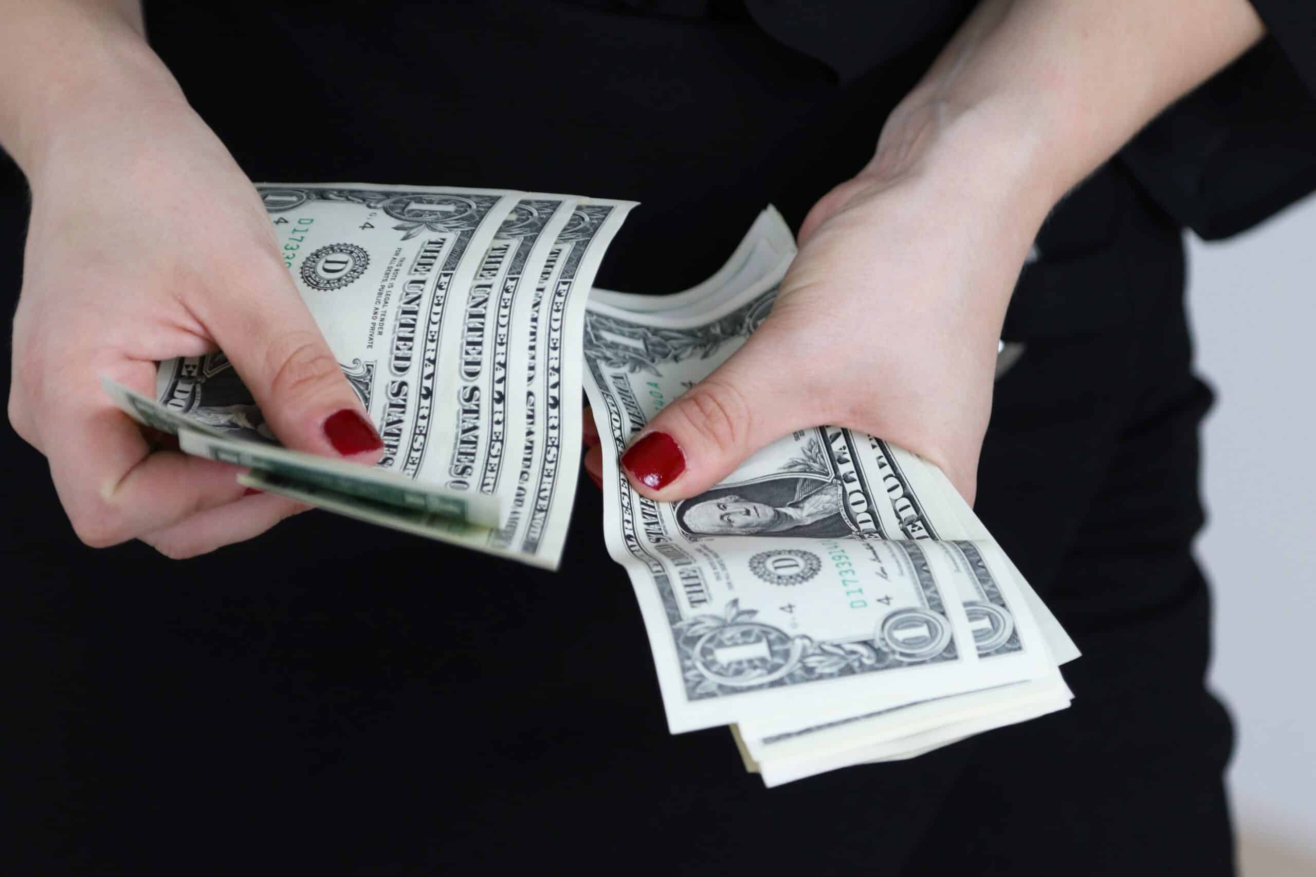 A woman counting dollar bills.